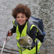 Child picks up rubbish from river bank