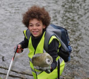 Child picks up rubbish from river bank